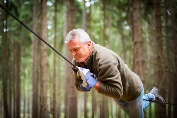 Mann zieht an einem Seil in einem Waldgebiet
