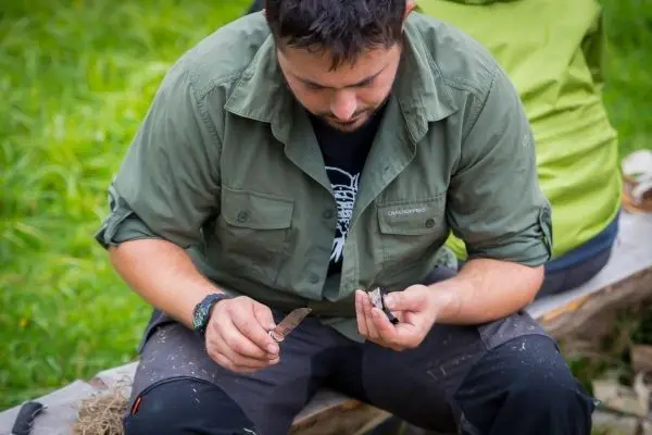 Messer wird in der Hand gehalten, während ein Holzstück bearbeitet wird