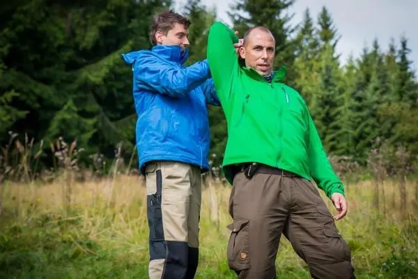 Person hilft Person beim Anziehen einer Jacke im Freien