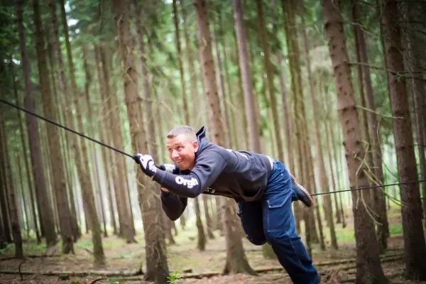 Person schwingt an einem Seil zwischen Bäumen