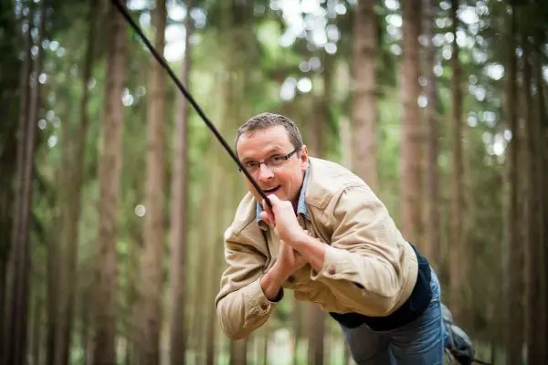 Person schwingt an einem Seil zwischen Bäumen