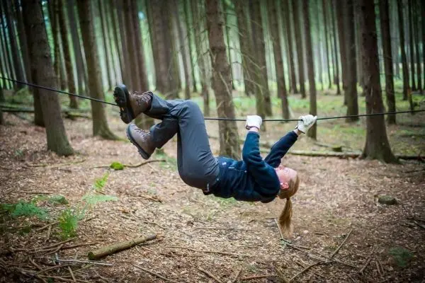 Person schwingt sich an einem Seil zwischen Bäumen