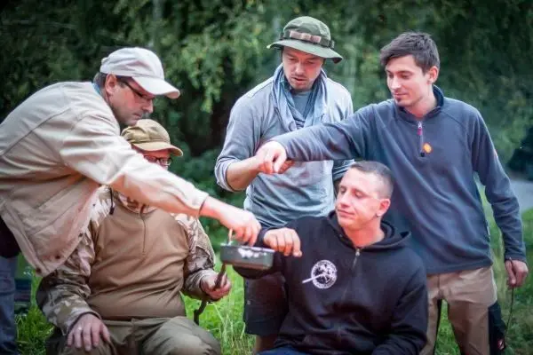 Personen teilen Essen aus einem Topf beim Überlebenstraining