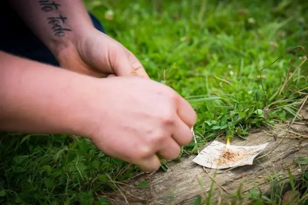 Zunder glimmt auf einem Blatt, Hand entzündet mit Funken