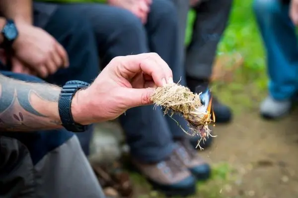 Zunder glimmt in Hand, kleine Flamme sichtbar