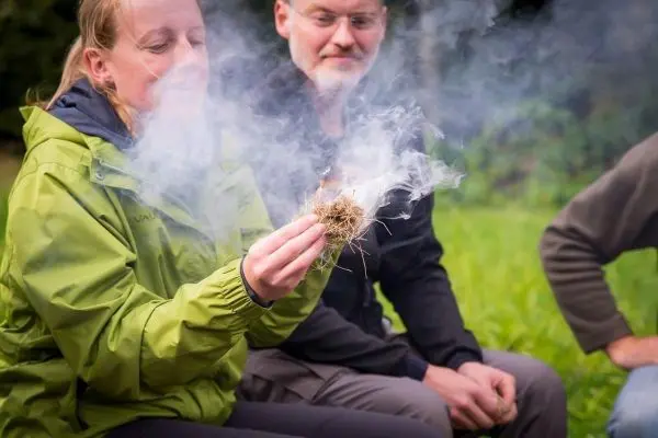 Zunder glimmt und erzeugt Rauch in der Hand einer Person