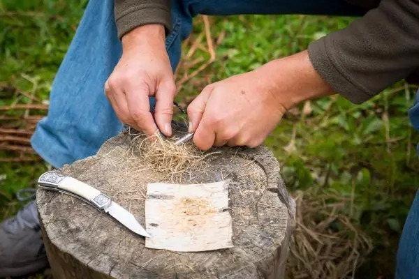 Zunder wird mit einem Messer auf einem Baumstumpf bearbeitet