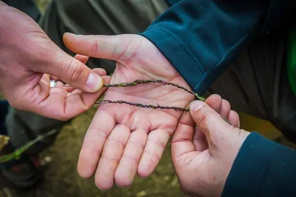 Zwei Hände flechten Pflanzenmaterial zu einer Schnur