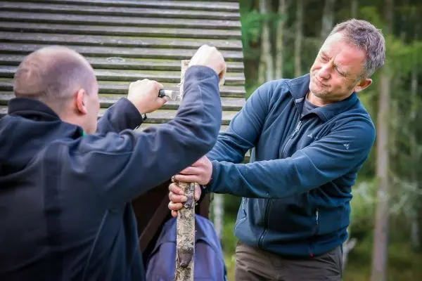 Zwei Personen befestigen einen Stock an einer Konstruktion