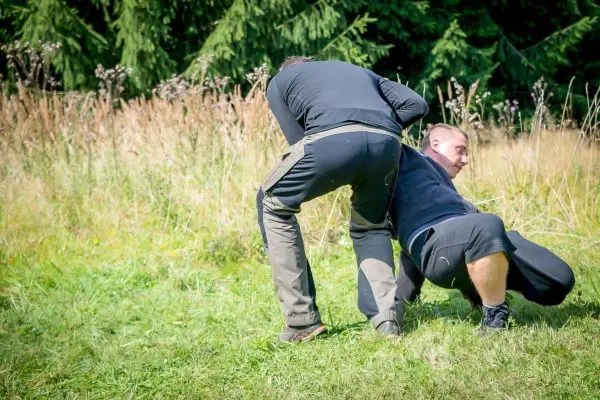Zwei Personen führen eine Technik zur Kontrolle des Gegners auf einer Wiese aus