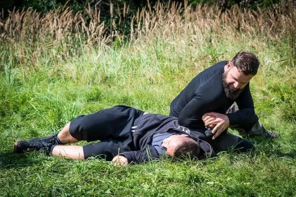 Zwei Personen im Ringen auf einer Wiese, einer hält den anderen am Arm