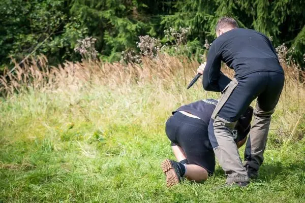 Zwei Personen in einer Wiese, eine Person hält einen Gegenstand über der anderen