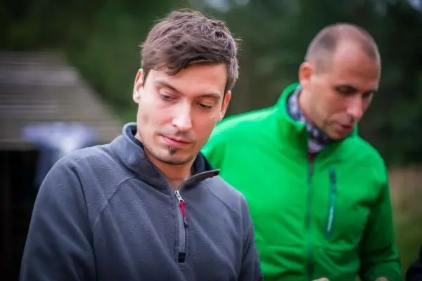 Zwei Personen in Outdoor-Bekleidung beschäftigen sich mit einer Tätigkeit im Freien