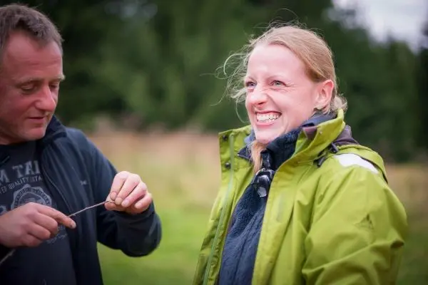 Zwei Personen interagieren im Freien, einer hält einen Stock in der Hand