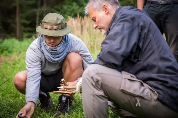 Zwei Personen knien im Gras und untersuchen eine selbstgebaute Konstruktion