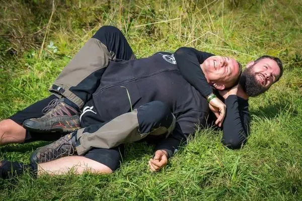 Zwei Personen liegen auf dem Gras und führen einen Bodenkampf durch