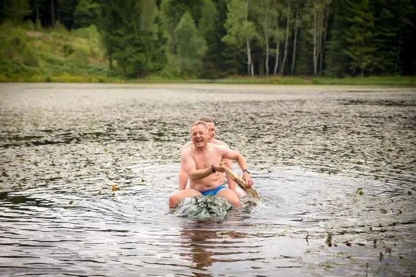 Zwei Personen sitzen auf einem schwimmenden Objekt im Wasser und lachen