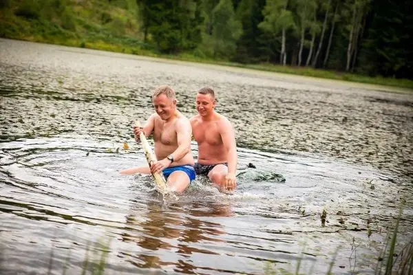 Zwei Personen sitzen im Wasser und halten einen Fisch