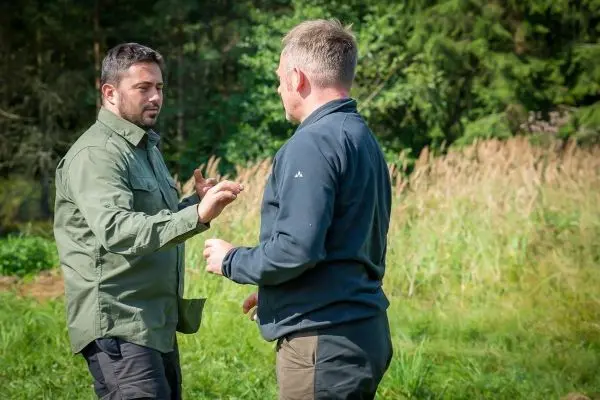 Zwei Personen stehen in einem grünen Feld und führen ein Gespräch