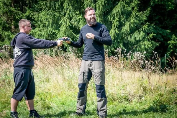Zwei Personen stehen in einer Wiese und führen eine Übergabe durch