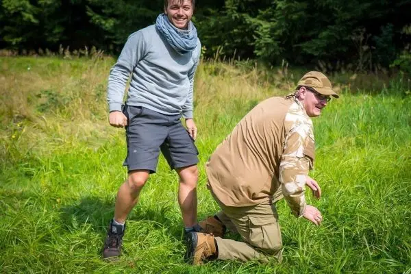 Zwei Personen stehen und knien auf einer Wiese