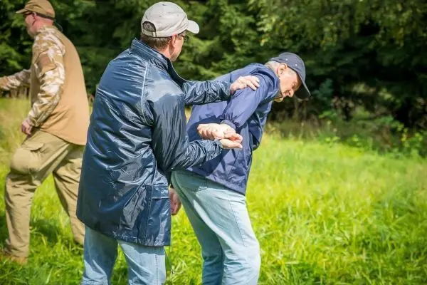 Zwei Personen üben eine Festnahme im Freien auf einer Wiese