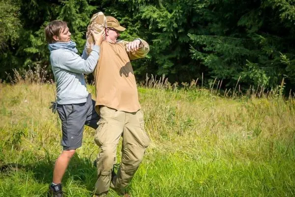 Zwei Personen üben eine Selbstverteidigungstechnik im hohen Gras