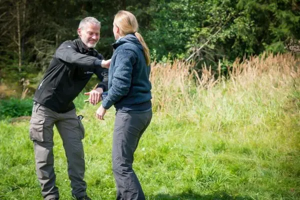 Zwei Personen üben eine Technik im Freien auf einer Wiese