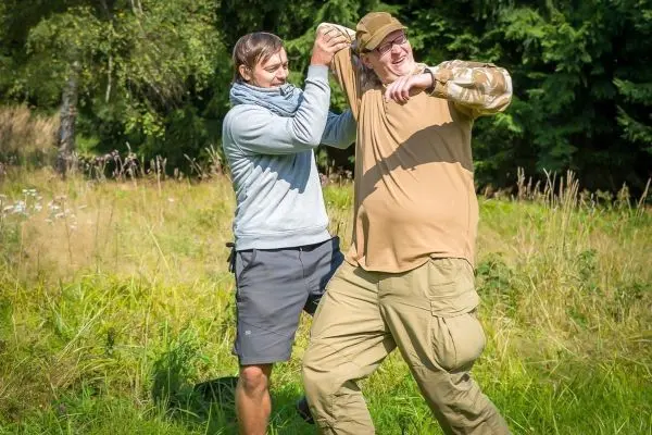 Zwei Personen üben eine Technik zur Befreiung aus einem Griff in einer Wiese