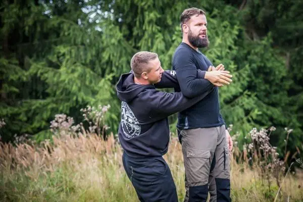 Zwei Personen üben eine Technik zur Selbstverteidigung im Freien