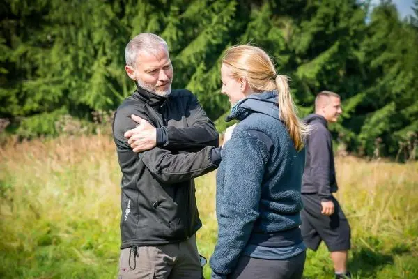 Zwei Personen üben eine Technik zur Selbstverteidigung im Freien