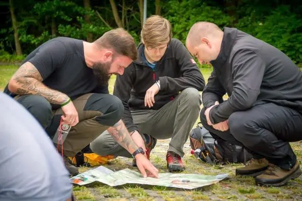 Drei Personen betrachten eine Karte auf dem Boden und diskutieren darüber
