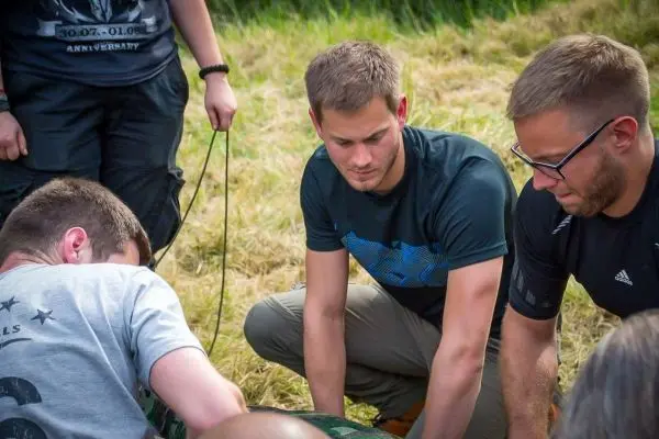 Drei Personen beugen sich über eine Ausrüstung auf dem Boden