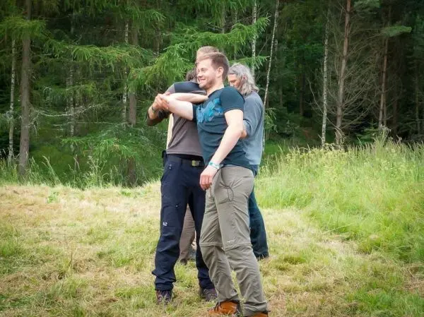 Drei Personen stehen auf einer Wiese und umarmen sich