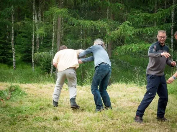 Drei Personen üben eine Technik zur Unterstützung oder Rettung im Gelände aus