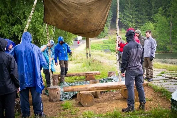 Gruppe von Personen baut eine Unterstandkonstruktion aus Planen auf