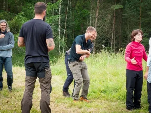 Gruppe von Personen interagiert in einer Wiese, einige lachen und gestikulieren