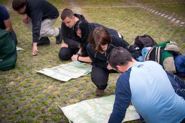 Gruppenteilnehmer studieren Karten auf dem Boden in einer Freiluftumgebung