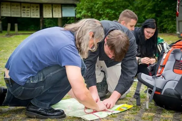 Gruppierung betrachtet eine Karte auf dem Boden, Rucksack im Hintergrund sichtbar