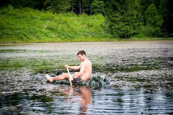 Jemand paddelt auf einem improvisierten Floß durch einen See