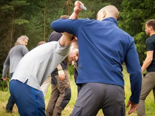 Kampfszenario mit zwei Personen, eine Person hält den Arm des anderen hinter dem Rücken