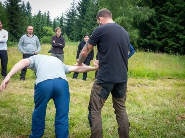 Kampftechniken werden demonstriert, während Teilnehmer aufmerksam zuschauen