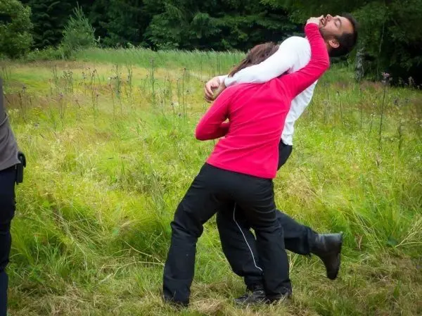 Kampftraining mit zwei Personen in einer Wiese, eine Person hält die andere im Griff