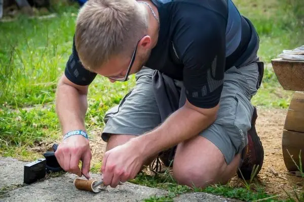 Mann bearbeitet Zunder mit einem Messer auf dem Boden