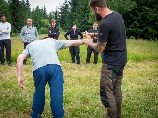 Mann demonstriert eine Technik zur Kontrolle eines anderen Mannes in einer Wiese