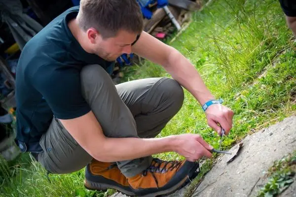 Mann kniet und schneidet mit einem Messer Gras oder Pflanzen