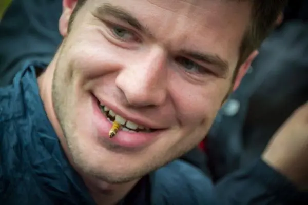 Mann mit einem Insekt im Mund lächelt in die Kamera