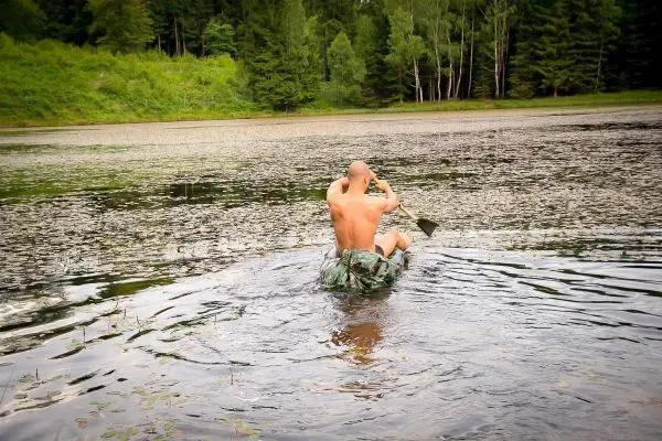 Mann paddelt in einem improvisierten Boot über einen ruhigen See
