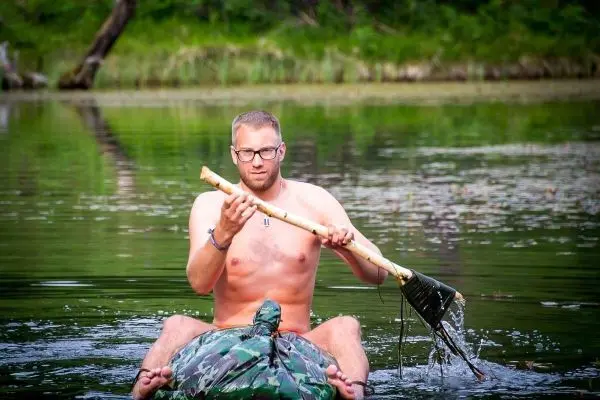 Mann paddelt mit einem Stock auf einem improvisierten Floß im Wasser