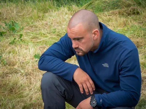 Mann sitzt auf dem Boden und schaut nachdenklich auf den Boden